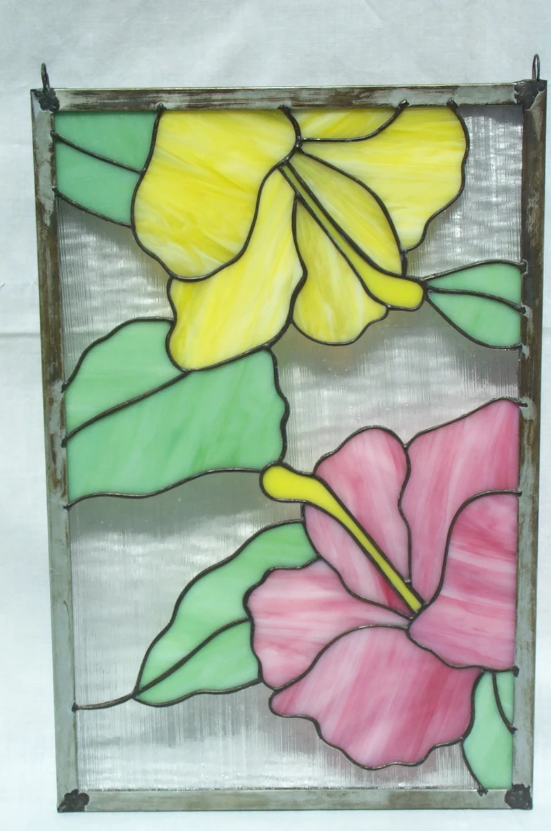 Rectangular stained glass window panel with a yellow hibiscus and a pink hibiscus with green leaves on clear textured glass