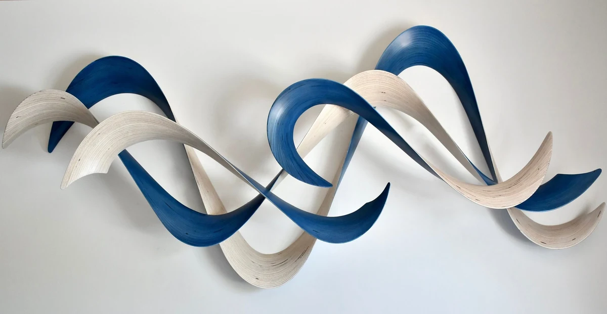 Wall sculpture of interwoven cobalt blue and cream wooden ribbons crossing in a dense braided wave