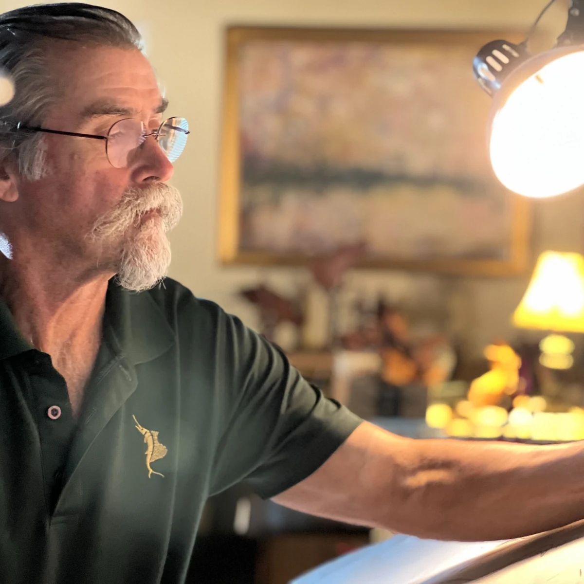 Geoffrey C. Smith sketching at his studio drafting desk under a lamp
