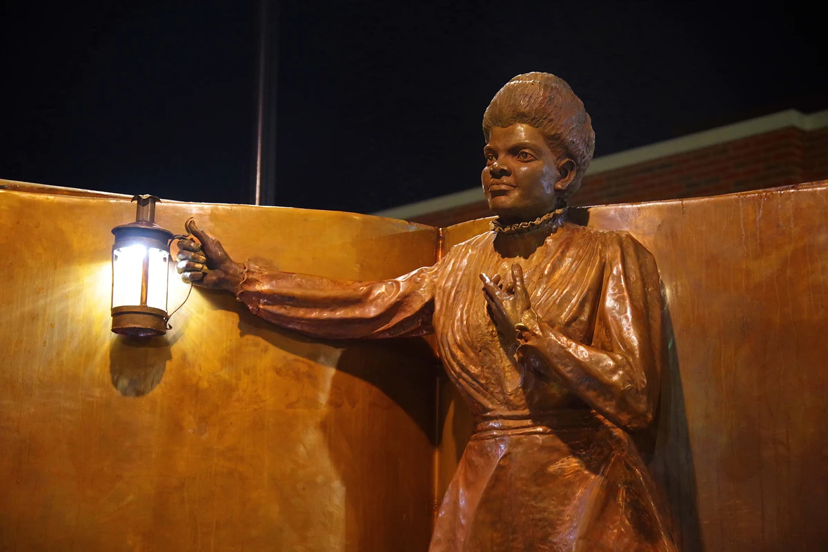 Copper figure of Ida B. Wells holding a lantern out over the open book of the "Light of Truth" monument, Ida B. Wells Middle School, Washington DC