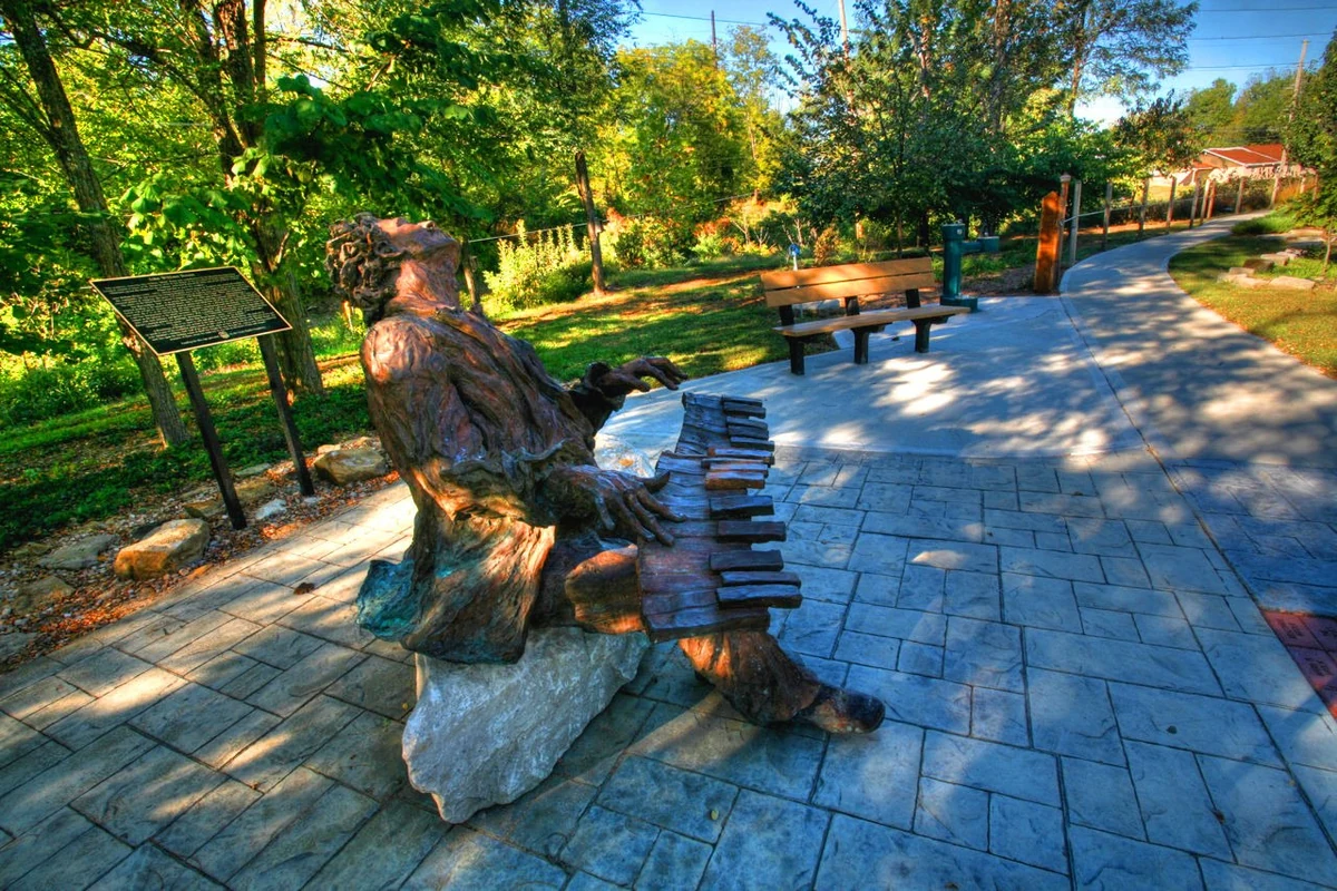 Bronze monument to ragtime musician John William "Blind" Boone, seated at a keyboard beside a park walkway
