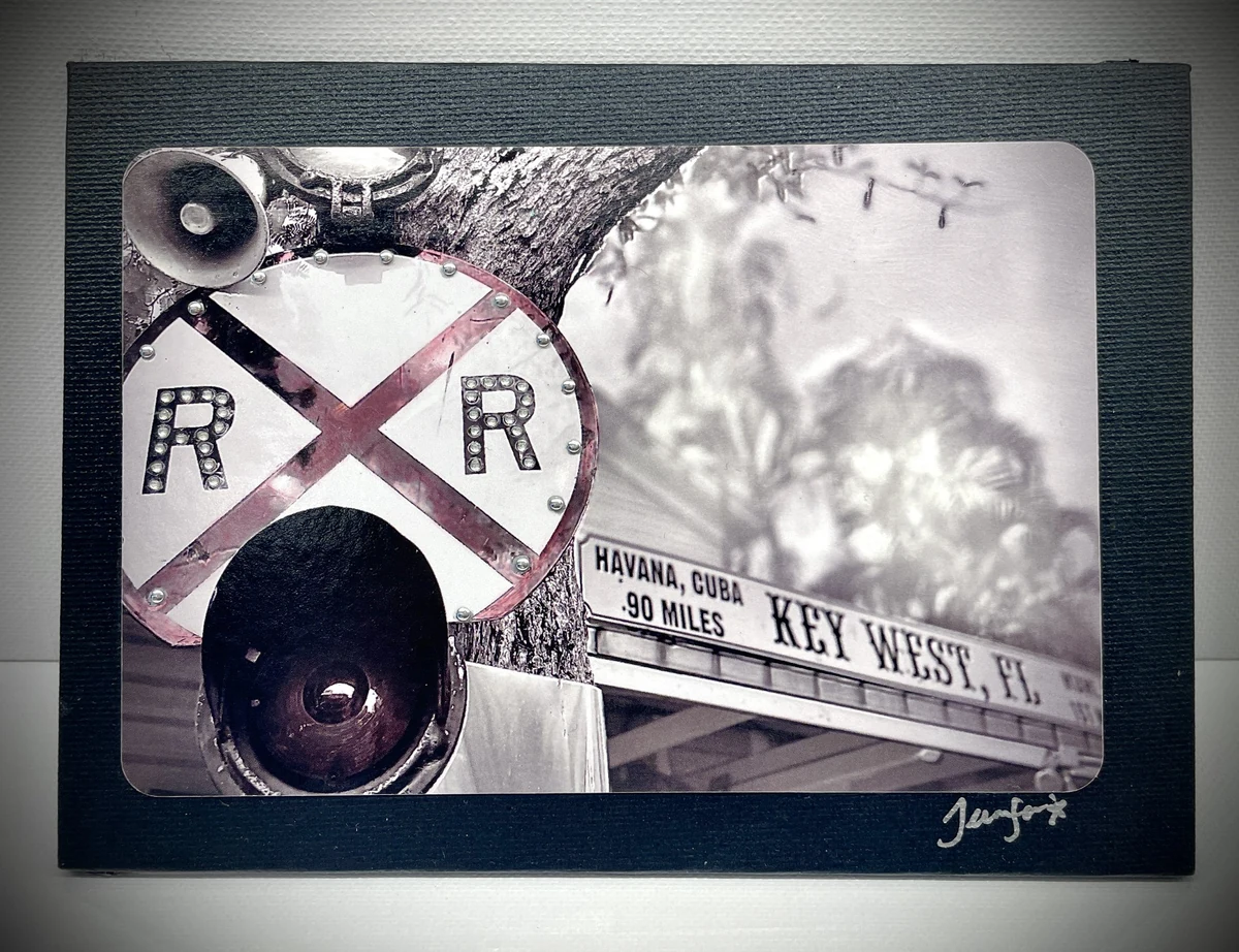 Framed black-and-white mixed-media collage combining a railroad crossing sign, a palm and a signpost reading HAVANA, CUBA 90 MILES / KEY WEST, FL, signed lower right