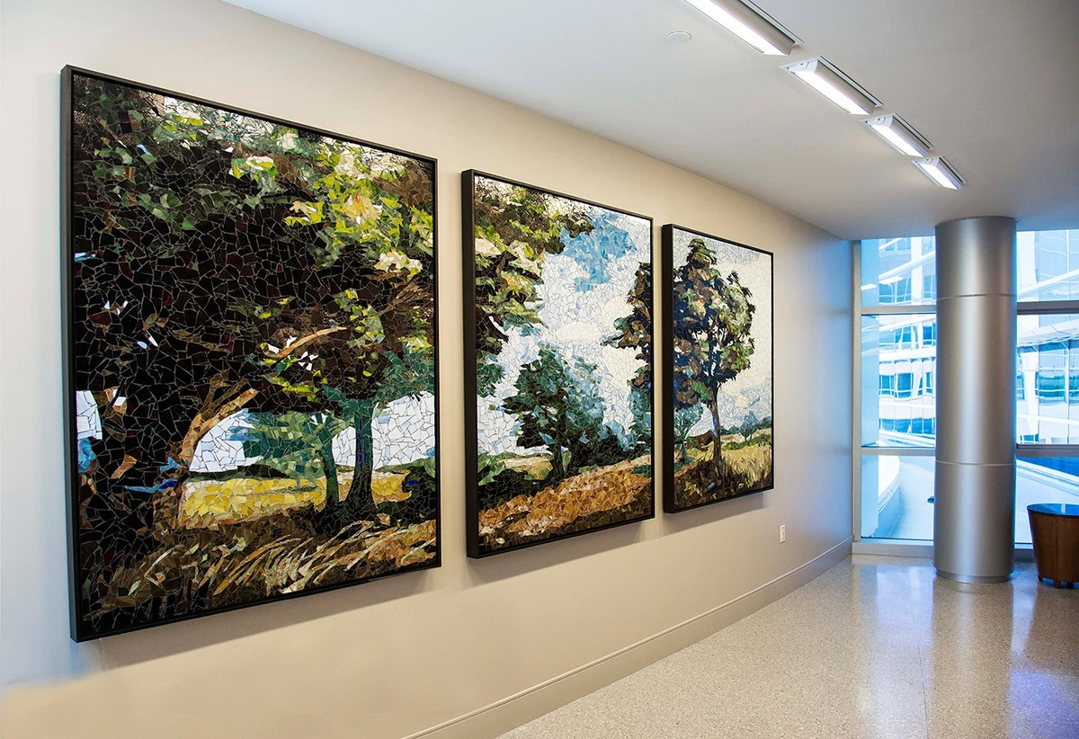 Three-panel glass mosaic landscape of wind-bent trees, installed in a corridor at Memorial Hermann Memorial City Medical Center