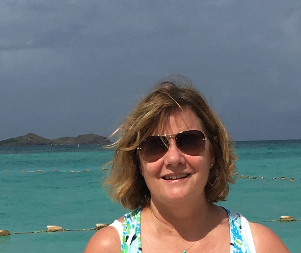 Kathy Corey photographed at the shoreline, turquoise water and a small key behind her