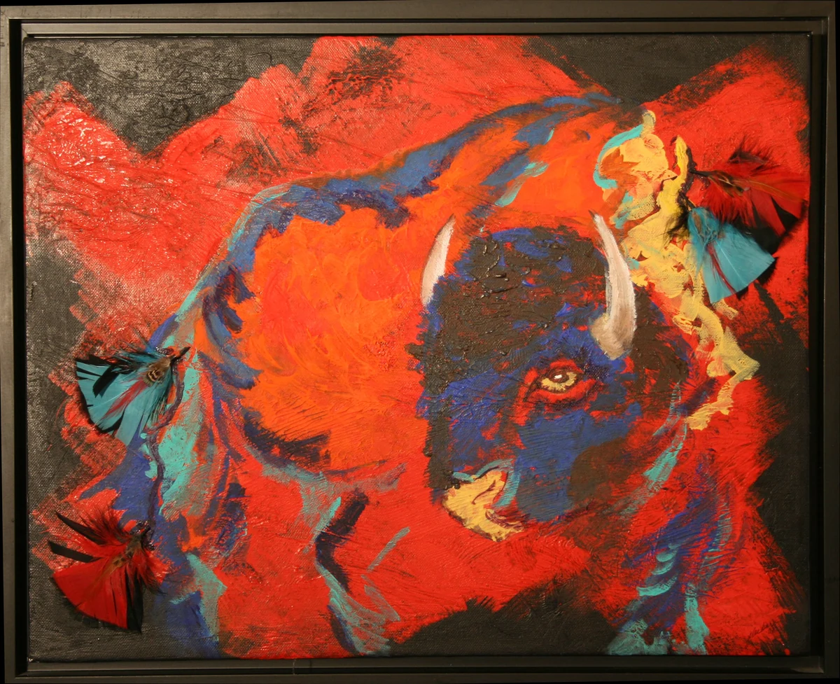 Framed mixed media painting of a bison in red, orange and blue, with real feathers attached to the canvas